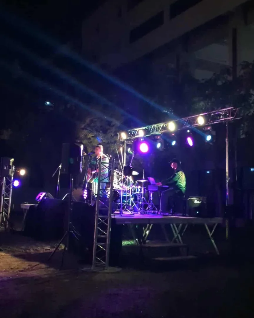 Un guitariste chanteur et un batteur sur la scène en plein air, dans un faisceau violet et ambré.